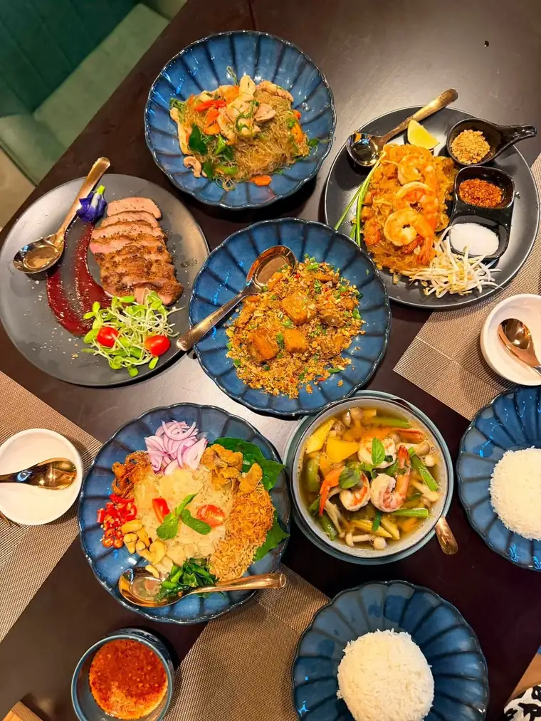สำรับอาหารไทยหลายจานของร้านเสน่หาบนโต๊ะไม้